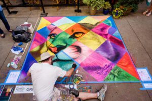 Artist drawing colorful pop art of lion with chalk in market square downtown knoxville during Dogwood arts chalk walk 