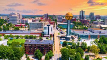 Aerial view of downtown Knoxville at sunset, with the gold Sunsphere tower and modern buildings nearby