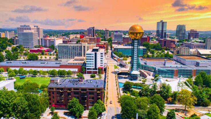 Aerial view of downtown Knoxville at sunset, with the gold Sunsphere tower and modern buildings nearby