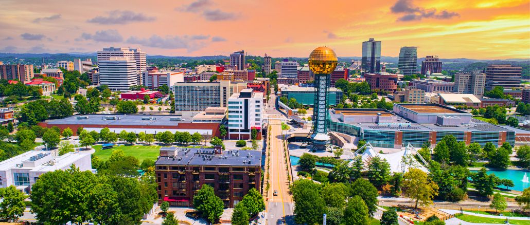 Aerial view of downtown Knoxville at sunset, with the gold Sunsphere tower and modern buildings nearby